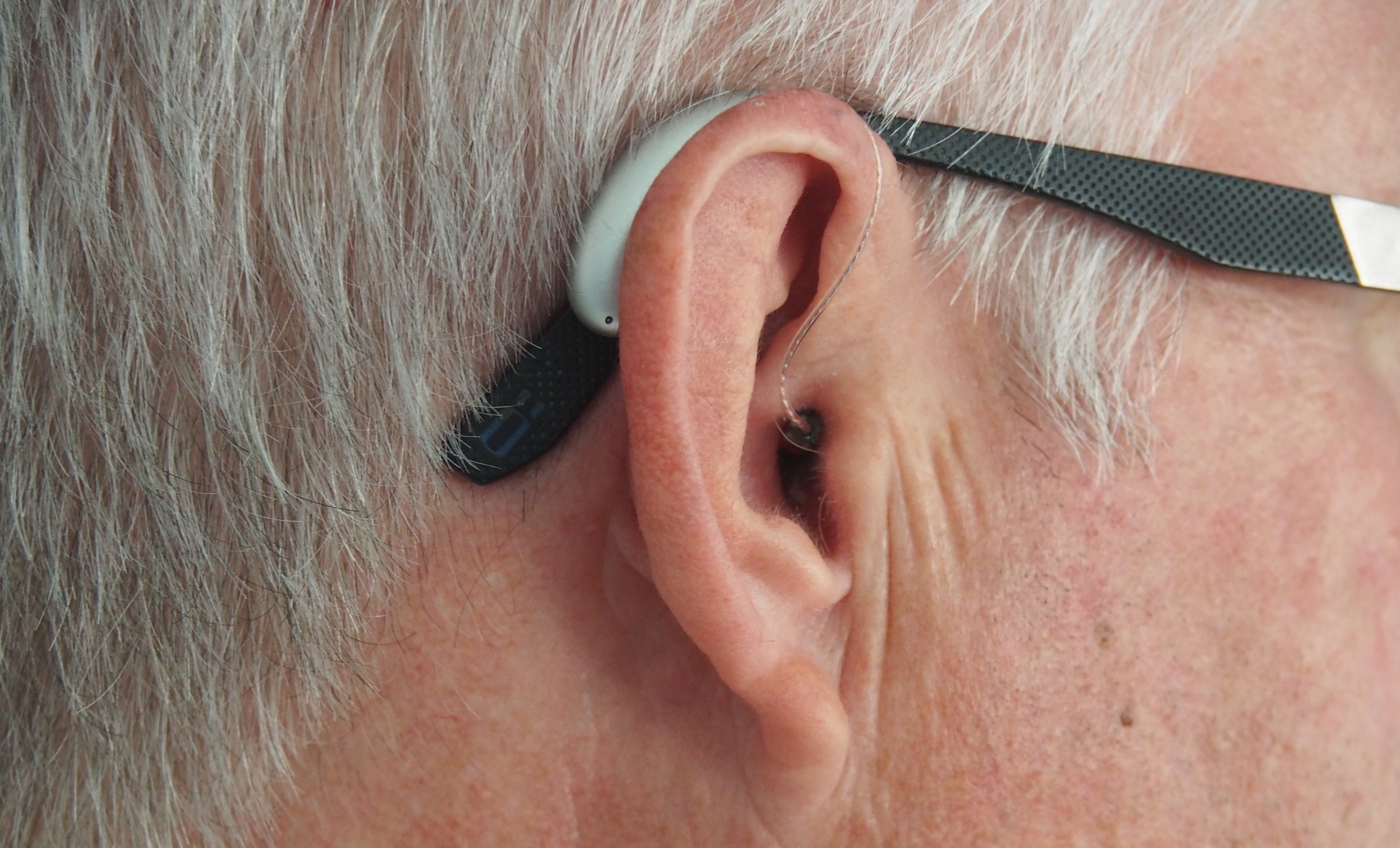 Close up of the ear of an older white man. Photo by Mark Paton on Unsplash