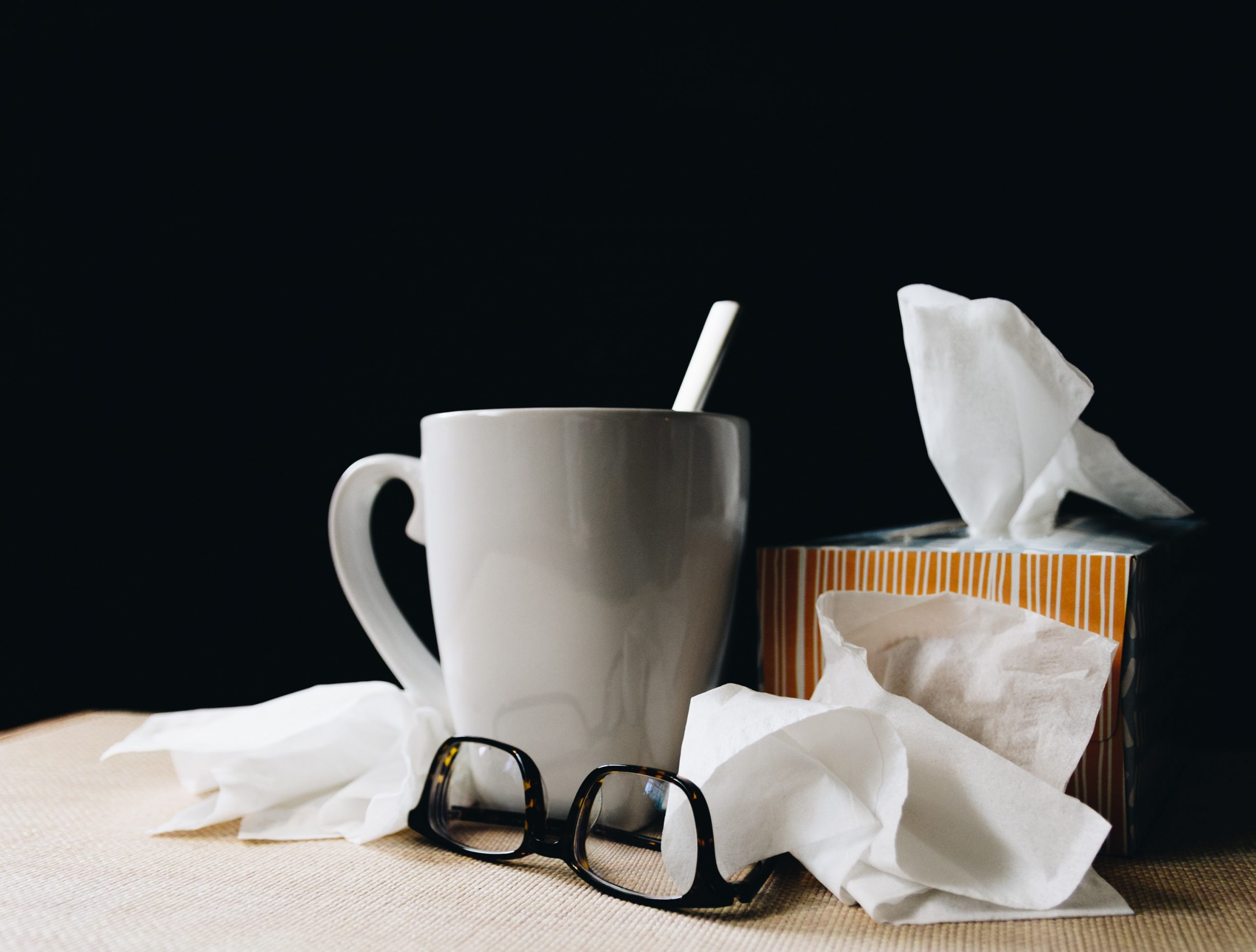 A box of tissues on atable next to a mug and a pair of glasses. Photo by kelly-sikkema on Unsplash.com