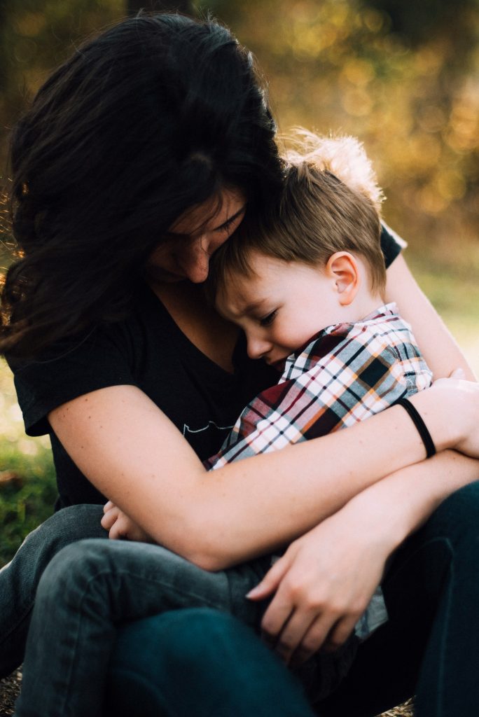 A mother hugs and consoles a young boy. Photo by Jordan Whitt on Unsplash.com
