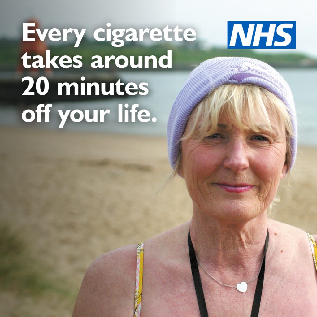 Older woman wearing a hat stands on a beach. Text reads: “Every cigarette takes around 20 minutes off your life” with the NHS logo.